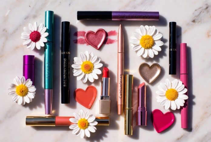 Editorial flatlay of bold luxury makeup products with charm-motif packaging representing the Marc Jacobs Beauty Sephora return and maximalist relaunch collection launching June 1 2026
