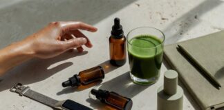 Curated wellness lifestyle flat lay with wearable tracker, supplement bottles, green smoothie, and skincare serum representing the longevity biohacking movement in 2026