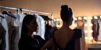 A red carpet stylist making final adjustments to a custom gown backstage representing Runway Magazine's complete guide to the stylists behind the biggest red carpet fashion moments