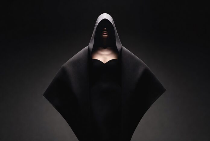 Balenciaga Runway 2026 — ClairObscur Fall/Winter Collection by Pierpaolo Piccioli Model in dramatic oversized cocooning coat on a pitch-black runway with chiaroscuro spotlight lighting representing the Balenciaga runway 2026 ClairObscur collection by Pierpaolo Piccioli at Paris Fashion Week
