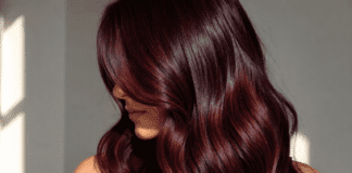 Cinematic editorial close-up of glossy cherry cola hair in deep burgundy-brunette tones with warm red highlights representing the most requested celebrity hair color trend of 2026