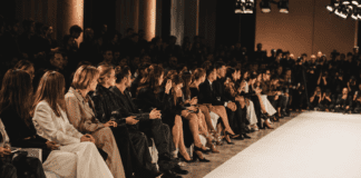 Editors and guests seated front row at a Milan Fashion Week runway show, representing the power players and seating hierarchy covered by Runway Magazine's Spring 2026 front row profile