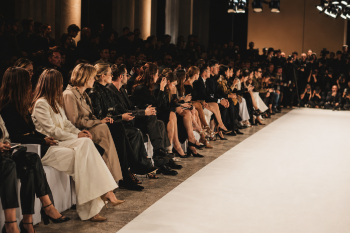 Editors and guests seated front row at a Milan Fashion Week runway show, representing the power players and seating hierarchy covered by Runway Magazine's Spring 2026 front row profile