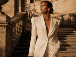 The 2026 Fashion Shift: How the New Maximalism Is Rewriting the Style Rulebook Model in a structured ivory wide-shoulder blazer with gold accessories on a sunlit stone staircase representing the new maximalism fashion trend in spring summer 2026
