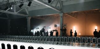 Empty New York Fashion Week runway with production crew preparing the venue before the show, illustrating how the NYFW schedule is built and sequenced