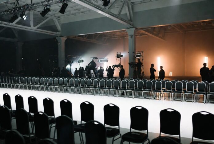 Empty New York Fashion Week runway with production crew preparing the venue before the show, illustrating how the NYFW schedule is built and sequenced