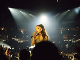 Ariana Grande New Music Is Driving Major Streaming and Billboard Activity A glamorous pop superstar performing on a brightly lit arena stage with a microphone, evoking a major comeback tour
