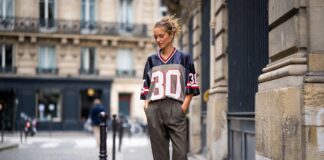 A stylish person outside Paris Fashion Week in a vintage football jersey, tailored trousers, and Adidas Sambas