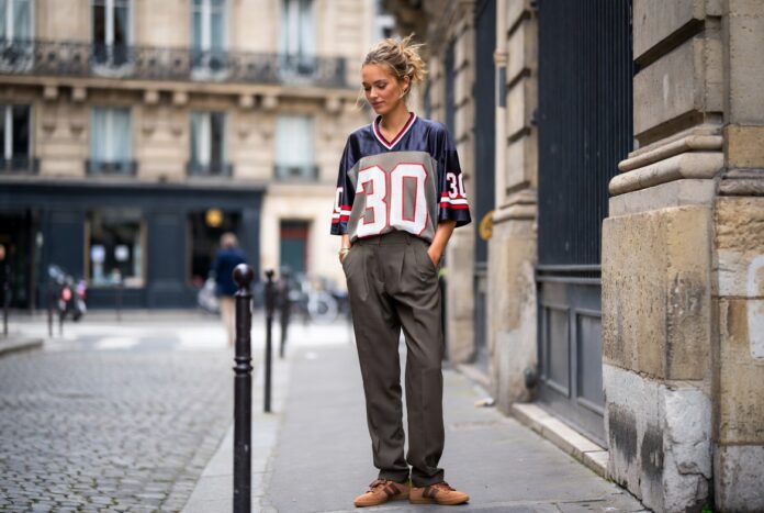 Blokecore Fashion Paris Street Style Football Jerseys A stylish person outside Paris Fashion Week in a vintage football jersey, tailored trousers, and Adidas Sambas