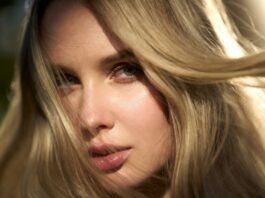 Model with glossy warm blonde hair in soft natural light showing a creamy, luminous finish.