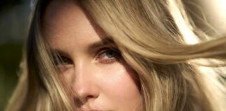 Model with glossy warm blonde hair in soft natural light showing a creamy, luminous finish.