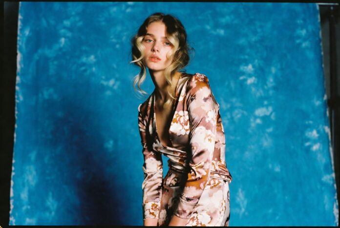 Young British model in floral luxury dress against vibrant blue backdrop representing Jacqui Hooper model's rise from Reading Festival scouting to Vogue Korea cover and luxury fashion campaign bookings in 2026