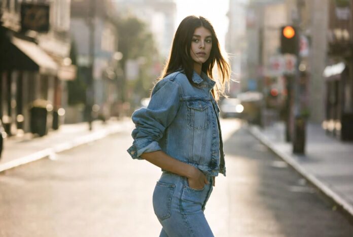 Kaia Gerber's 2026 Fashion Powerhouse Era Model in a relaxed denim look walks a sunlit street with an effortless, off-duty pose.