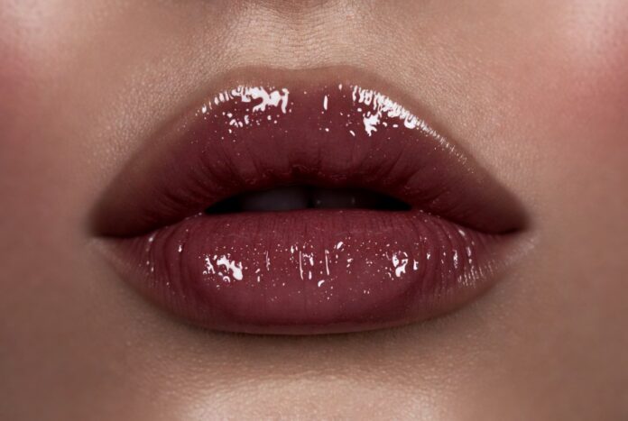 Close-up of lacquered high-shine berry lips in luxury beauty editorial lighting representing the lacquered lips trend 2026 and the shift from matte lipstick to gloss-balm hybrid formulas in celebrity makeup and high fashion beauty