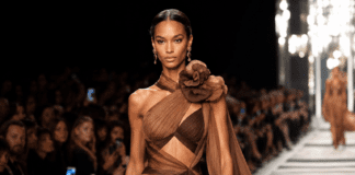 A high fashion model walking a luxury runway show in an elegant designer look under bright runway lighting