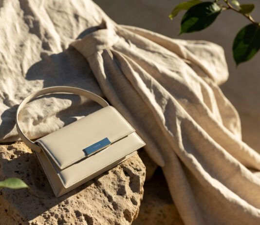 A luxury handbag and garment made from recycled and upcycled materials displayed in soft, elegant natural light