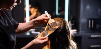 Colorist applying rich warm hair color to a client in a luxury salon representing the celebrity colorist as brand phenomenon in 2026 and the rise of Tracey Cunningham Chris McMillan and Chase Kusero as hair industry beauty influencers