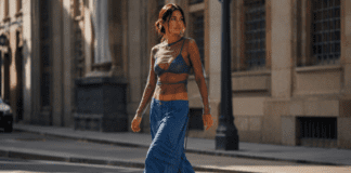 Woman in ocean-blue wide-leg cargo pants and a sheer layered top walking on a sunlit city street.