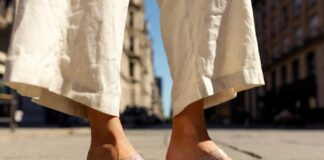 Jelly Shoes, Beaded Sandals and ’90s Footwear Are Fueling Summer Street Style Woman wearing translucent jelly sandals with a cream linen co-ord on a sunlit summer city street.