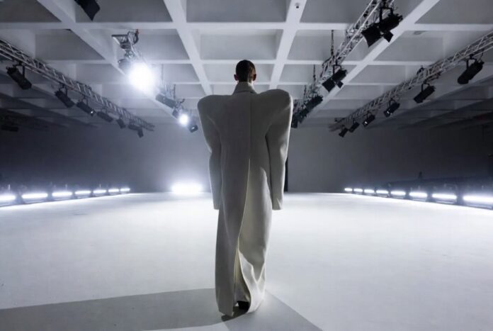 Model in architectural oversized Balenciaga coat on a stark runway representing Demna Balenciaga collections and the controversial creative tenure documented in Runway Magazine's complete guide