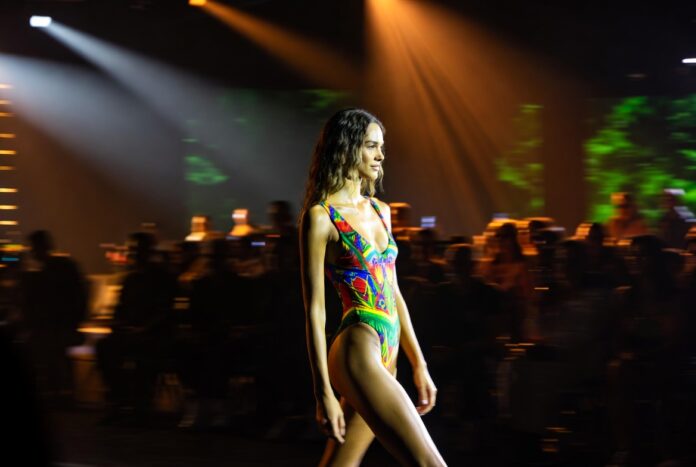 Model in vibrant tropical-print swimsuit on the PARAISO Collins Tent runway representing Luli Fama's SS27 collection at Miami Swim Week 2026 and the brand's 20th anniversary celebration of bold Latin-inspired luxury swimwear by Lourdes Luli Hanimian