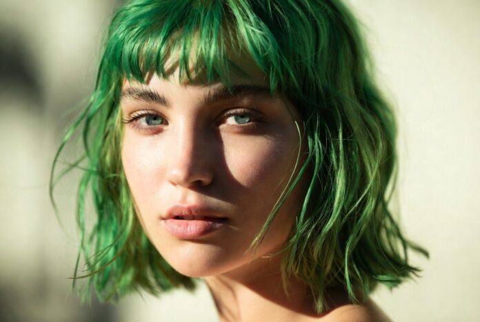Model with vibrant saturated neon green hair in warm summer editorial lighting representing the neon green hair trend and bold hair colors summer 2026 comeback in beauty culture and fashion