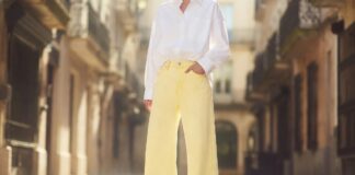 Pastel Denim Is Emerging as Summer’s Unexpected Street Style Favorite Fashion figure in butter yellow wide-leg pastel denim jeans with white oversized shirt on sunlit European street representing the pastel denim trend 2026 and the shift from indigo to soft pastel shades in summer street style