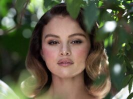 Selena Gomez’s Romantic Rare Beauty Campaign Is Fueling the Fairy Makeup Movement Woman in white tulle dress in a lush garden with rosy pink blush shimmering eyeshadow ultra-glossy lips and soft waves representing the Selena Gomez Rare Beauty fairy makeup aesthetic and garden photoshoot beauty look from the June 2026 campaign
