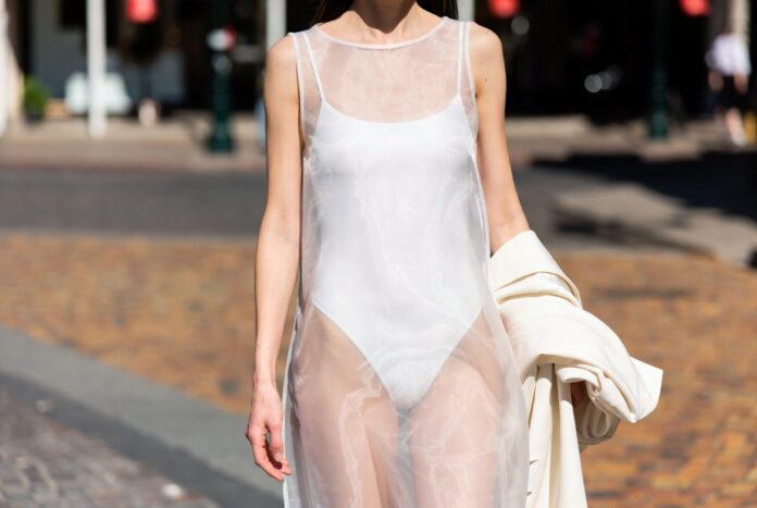 Model in a sheer fashion trend look wearing organza over a fitted bodysuit on a summer street representing Runway Magazine's complete guide to the sheer layering trend of 2026