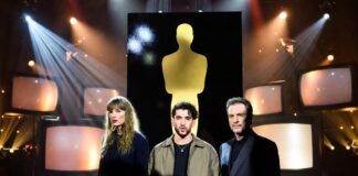 Gold awards statuette scene with TV screens, concert lights and red-carpet reflections