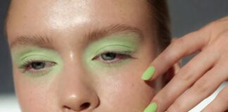 A model with a fresh pastel green eye look and glowing skin beside a crisp green apple manicure