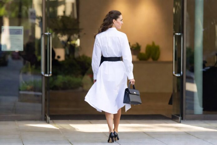 Polished white shirtdress with black belt and kitten heels in a refined summer setting