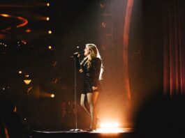 A pop singer stepping into a spotlight on a Las Vegas concert stage during a residency show