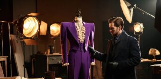 Image architect examining a dramatic purple tailored stage suit inside an elegant private fashion studio
