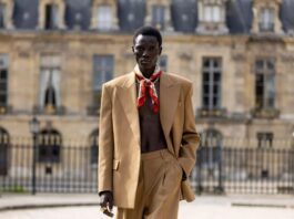 A model on a Paris runway in a tailored Celine look with silk scarf and gold accessories at a fashion show