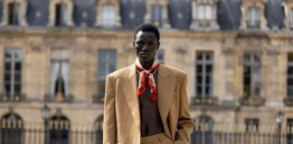 A model on a Paris runway in a tailored Celine look with silk scarf and gold accessories at a fashion show