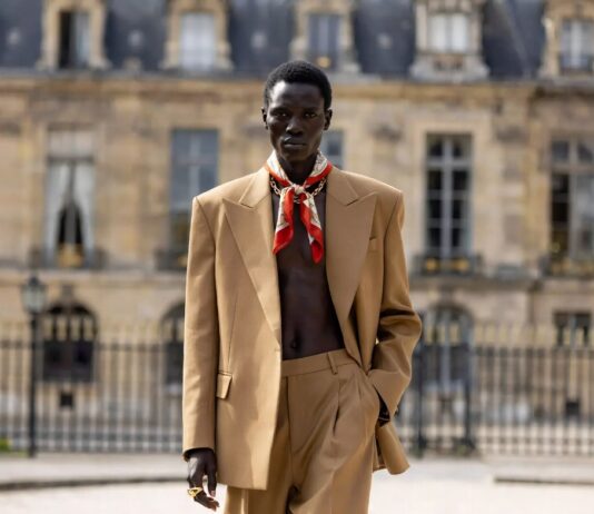Michael Rider Celine: The Acclaimed Debut That Reshaped Paris Fashion A model on a Paris runway in a tailored Celine look with silk scarf and gold accessories at a fashion show