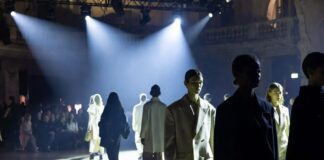 Young models walking a dramatic runway with luxury campaign energy and blurred audience