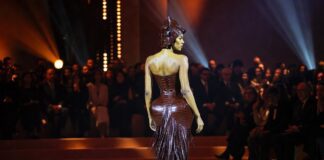 Teyana Taylor Ashi Studio Turned Couture Into a Viral Sitting Challenge Sculptural dark leather armor-inspired couture look with fringe at a Paris fashion show